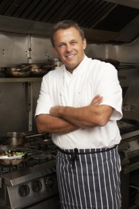 Male Chef Standing Next To Cooker In Restaurant Kitchen