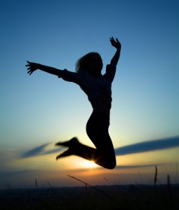 Silhouette of a girl jumping over sunset