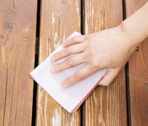 Female hand sanding cedar wood deck